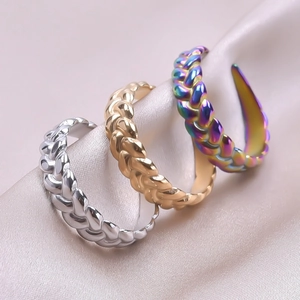 Three woven open rings in silver, gold and rainbow finish on champagne satin background