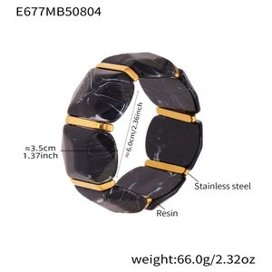 Dettagli di cubi in resina marmorizzata e distanziali in acciaio su bracciale elastico
