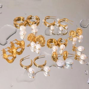 Golden stainless steel earrings collection with natural freshwater pearls on mirror background