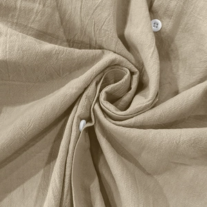 Dettaglio macro della trama in lino beige e bottone bianco su una camicia a maniche lunghe