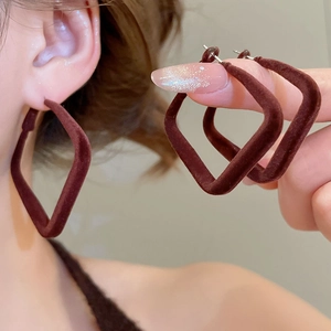 Détail de boucles d'oreilles pendantes carrées floquées marron foncé avec texture velours