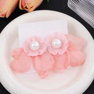 Detailed macro of pink lace flower earrings with pearl centers on ceramic tray
