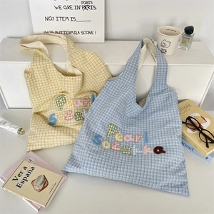 Detail of checkered canvas tote bags with colorful Pearl Sozakka letter embroidery