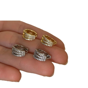 Three-row diamond-encrusted gold and silver hoop earrings held in hand for display
