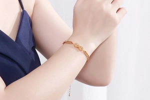 Polished gold titanium infinity symbol bracelet on a woman's wrist with link chain