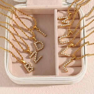 Detail of 18K gold plated twist chain necklaces with pearl initials in a pink velvet box