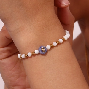 Close-up of white beads and blue hexagonal stone bracelet on female wrist