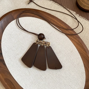 Detail view of vintage brown resin and wood geometric pendant with golden metal links
