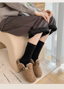 Detailed close-up of fuzzy brown slippers with thick white lining and buckle detail