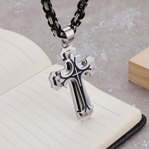 Detail of a bold men's cross pendant on a heavy emperor chain on a notebook