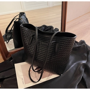 Close-up of black woven leather tote bag with fine texture on silk fabric