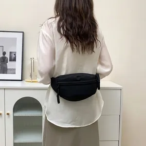 Detail view of a black minimalist chest bag with woven zipper pullers on a model