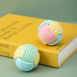 Colorful hand-woven cotton rope cat toys balls in vibrant candy colors on yellow book