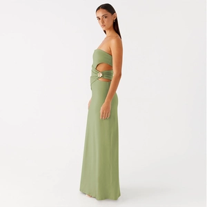 Detalle de vestido largo verde con abertura en la cintura y hebilla dorada