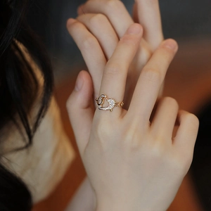 Close-up of gold chain ring with heart buckle and crystals on a model's finger