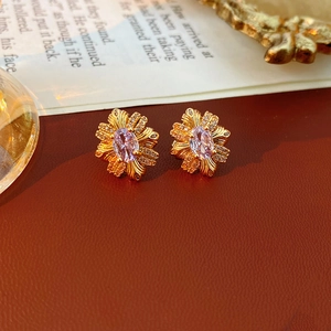 Gros plan sur boucle d'oreille fleur vintage avec zircon violet et pétales dorés
