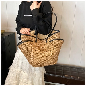 Detailed view of straw tote bag with wavy edges and black leather shoulder straps