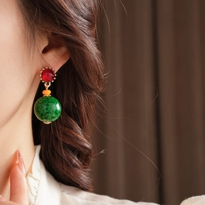 Gros plan de boucles d'oreilles vintage en céramique avec pendentifs verts et clous rouges