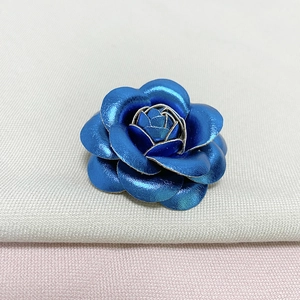 Macro shot of blue metallic leather camellia flower brooch with layered petals