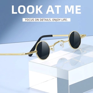 Retro small round punk sunglasses with gold metal frame and black lenses on blue backdrop