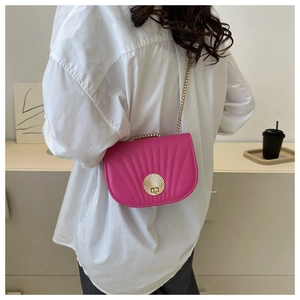Detail of hot pink saddle bag featuring radial pleats and golden seashell metal clasp