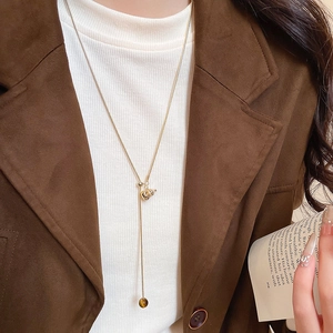 Close-up of golden tiger eye gourd pendant necklace worn on a brown blazer outfit