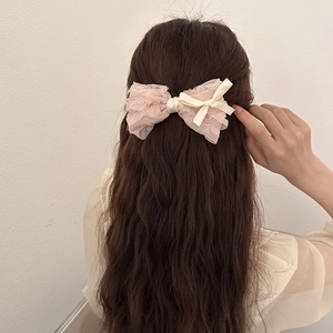 Pink lace tulle bow hair clip with cream satin ribbon on long wavy brown hair