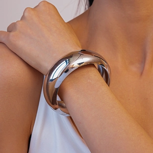 Close-up of polished silver wide bangle showing high mirror-like reflection and modern finish