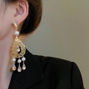 Close-up of golden pearl and crystal teardrop earrings in vintage French style
