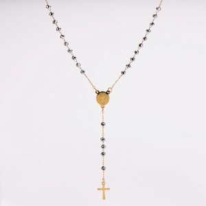 Detailed view of black faceted rosary beads with gold cross and holy medal on white background