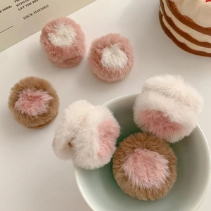 Detail of plush brown and white hair clips with pink centers on a white surface