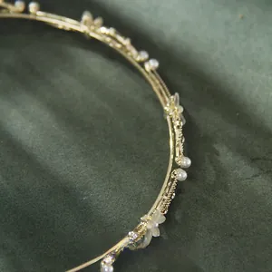 Detailed close-up of gold leaf headband with white pearls and frosted flowers on velvet