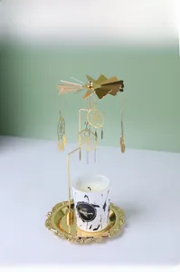 Detail of golden spinning dreamcatcher candle holder with feathers and embossed tray