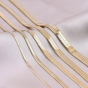 Detail of five gold flat snake chains in various widths from 2mm to 6mm on purple silk