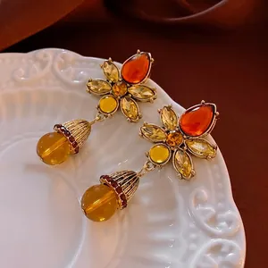 Vintage crystal flower drop earrings with amber resin beads on a decorative ceramic tray