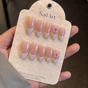Detail of pink French almond press-on nails with 3D embossed flowers and metal beads