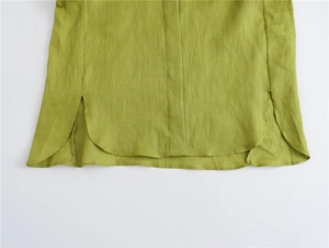 Dettaglio dell'orlo curvo e dello spacco laterale di questa camicia in lino verde