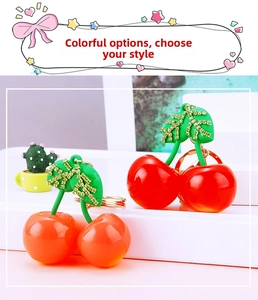 Detail view of sparkly cherry keychains with green rhinestones and golden metal ring