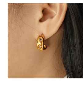 Detail of vintage gold hoop earring with colorful zircon stones on model's ear