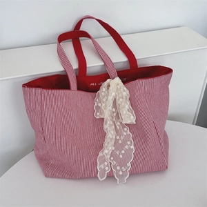 Detail der rot-weiß gestreiften Canvas-Tasche mit elegantem Spitzenschal am Tragegriff