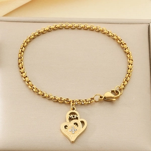 Détail d'un bracelet doré avec pendentif cœur gravé MOM et cristaux sur support cuir