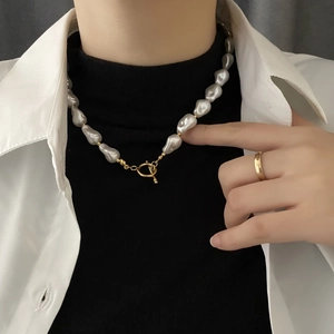 Irregular baroque pearl necklace with golden OT clasp shown on a model neck