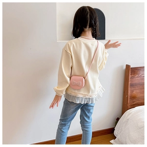 Detail of a pink mini crossbody bag with pearls and a lace hem sweatshirt for girls