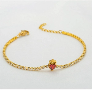 Macro shot of gold tennis bracelet with white zircons and a red heart crown charm