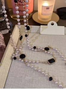 Detailed close-up of multilayered pearl necklace with black gemstones on a beige tray