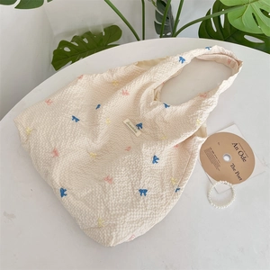 Gros plan du sac cabas en seersucker crème avec des motifs de nœuds colorés brodés