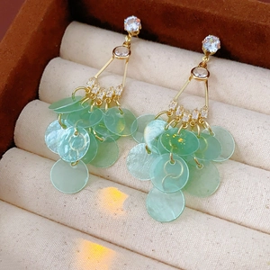 Detailed macro of gold-framed resin drop earrings with light green round pendants