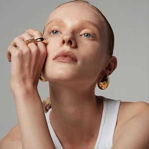 Vue macro de boucles d'oreilles en acier doré 16K et bagues minimalistes dorées