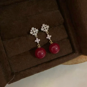 Macro shot of 18K gold plated flower earrings with red resin beads in a velvet jewelry box