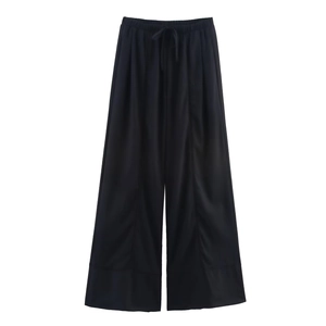 Detail of black wide-leg linen trousers with elastic drawstring waistband and fluid texture